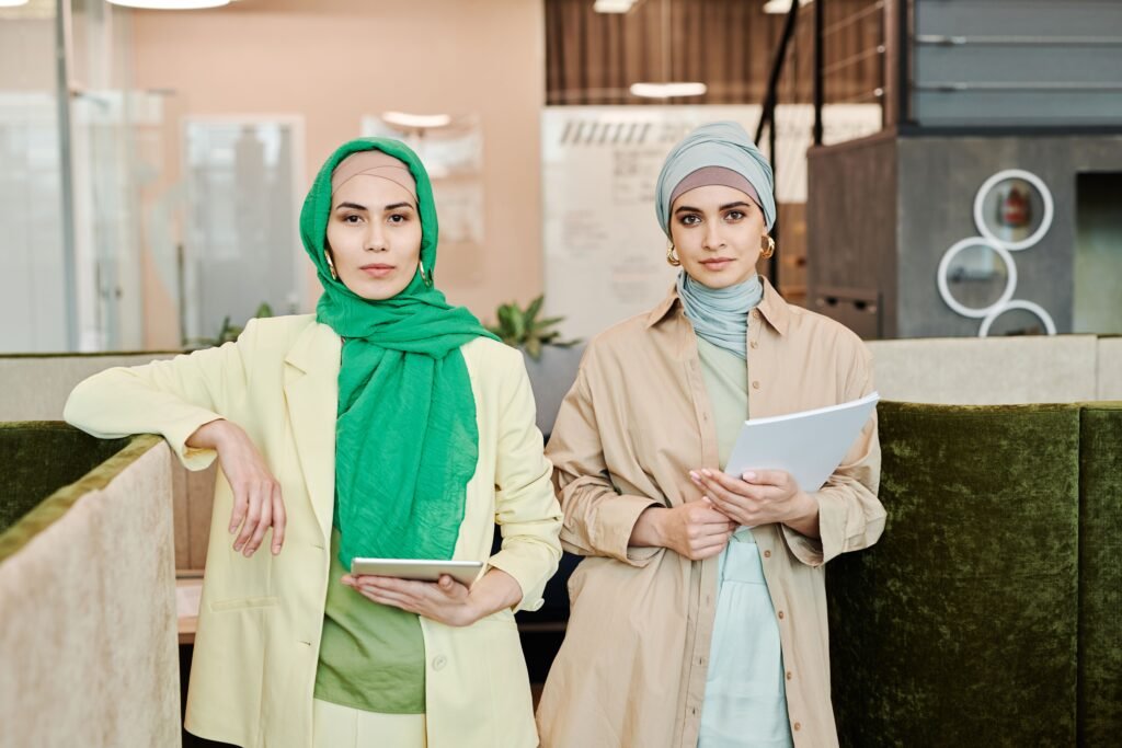 Two fashionable women in hijabs working together in a modern office environment.